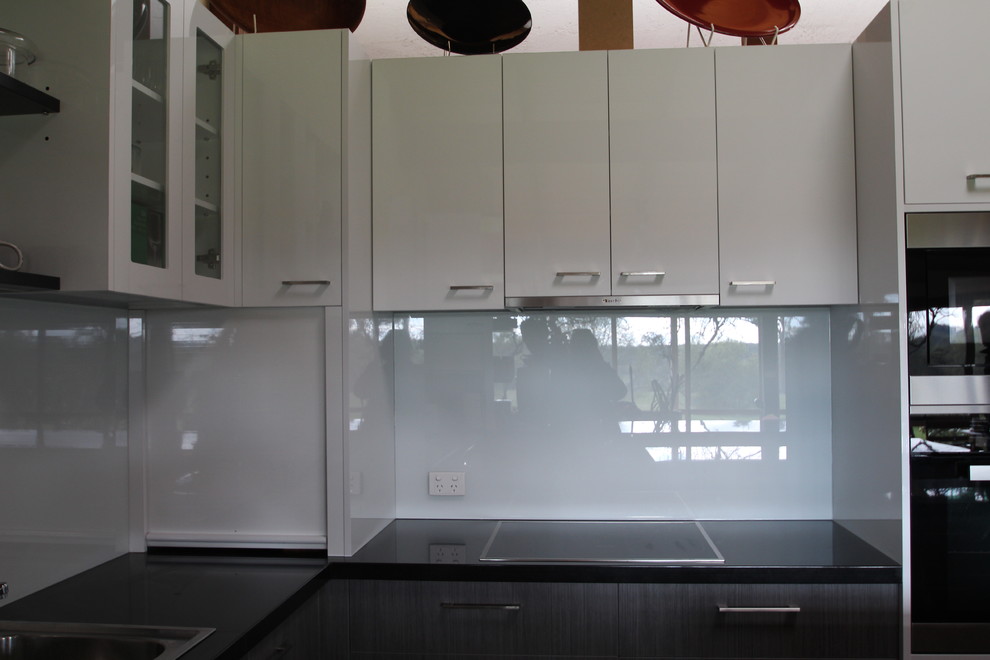 Design ideas for a large contemporary u-shaped open plan kitchen in Melbourne with a drop-in sink, flat-panel cabinets, grey cabinets, granite benchtops, white splashback, glass sheet splashback, stainless steel appliances, slate floors and multiple islands.