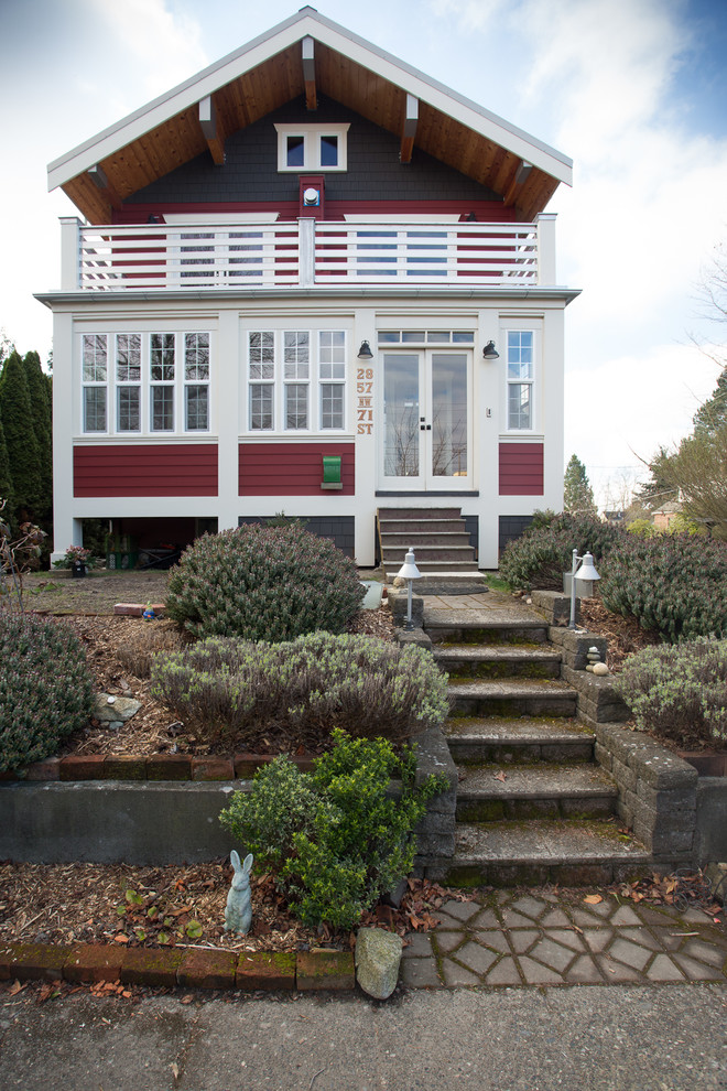 This is an example of a large country one-storey red house exterior in Seattle with wood siding, a gable roof and a shingle roof.