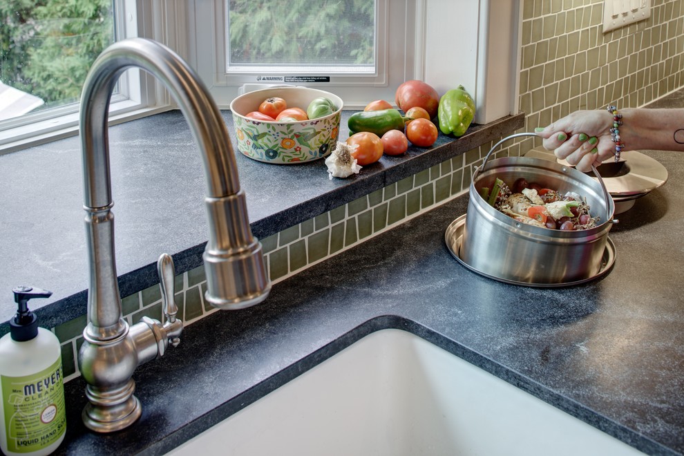 Mid-sized minimalist u-shaped slate floor kitchen photo in New York with a farmhouse sink, shaker cabinets, medium tone wood cabinets, granite countertops, glass tile backsplash, stainless steel appliances and an island