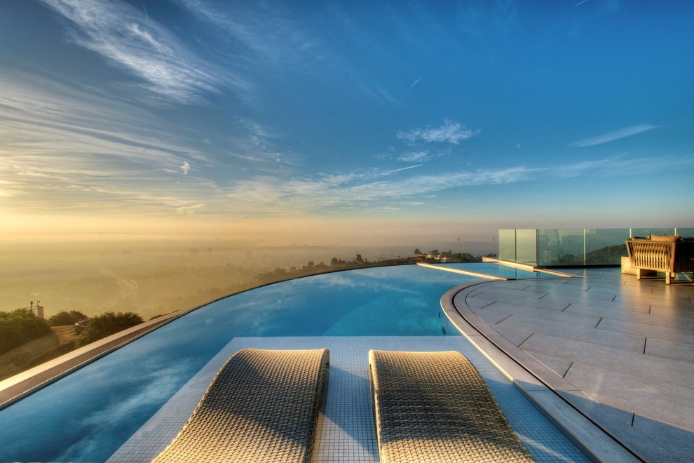 Large contemporary backyard kidney-shaped infinity pool in Los Angeles with a hot tub and tile.