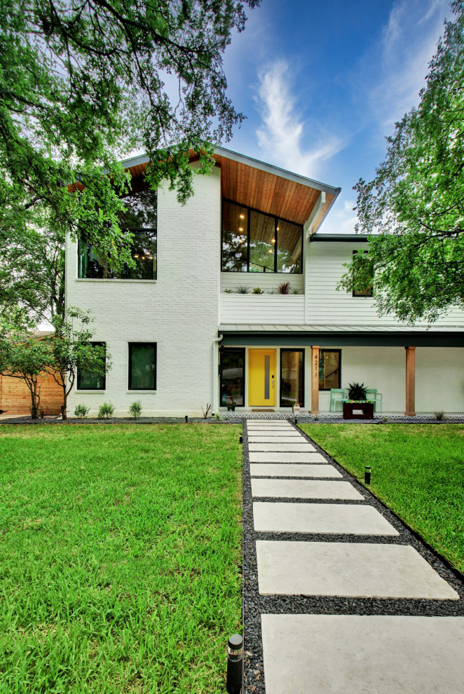 Example of a large danish white two-story brick exterior home design in Austin with a metal roof and a gray roof