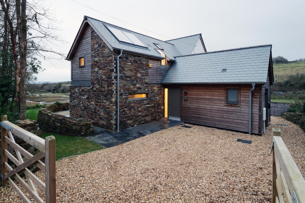 This is an example of a medium sized contemporary two floor side detached house in Cornwall with stone cladding, a pitched roof and a tiled roof.