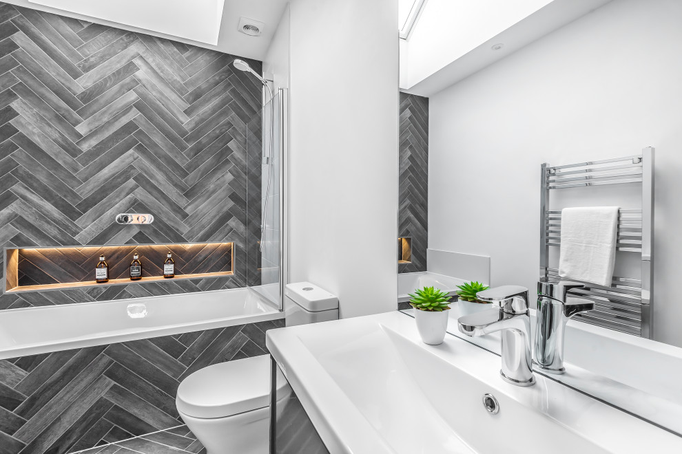 Modern inredning av ett vit vitt badrum, med släta luckor, grå skåp, ett badkar i en alkov, en öppen dusch, grå kakel, vita väggar, ett integrerad handfat och grått golv
