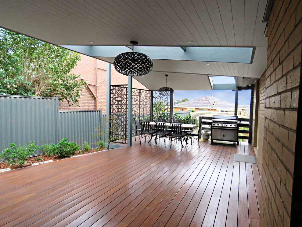 This is an example of a large modern backyard verandah in Melbourne with decking and a roof extension.