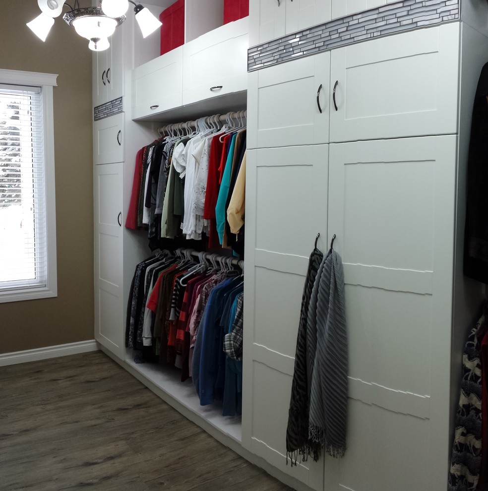 This is an example of a large modern gender-neutral dressing room in Calgary with shaker cabinets, white cabinets, vinyl floors and brown floor.