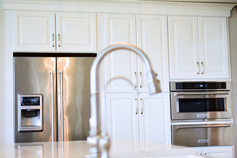 Eat-in kitchen - large transitional l-shaped medium tone wood floor and brown floor eat-in kitchen idea with a farmhouse sink, shaker cabinets, white cabinets, quartz countertops, white backsplash, marble backsplash, stainless steel appliances and two islands