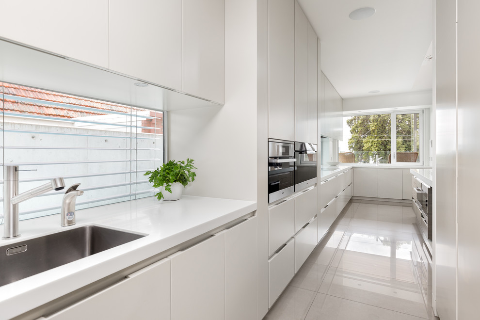 Photo of a large contemporary kitchen pantry in Geelong with an undermount sink, solid surface benchtops, porcelain floors and with island.