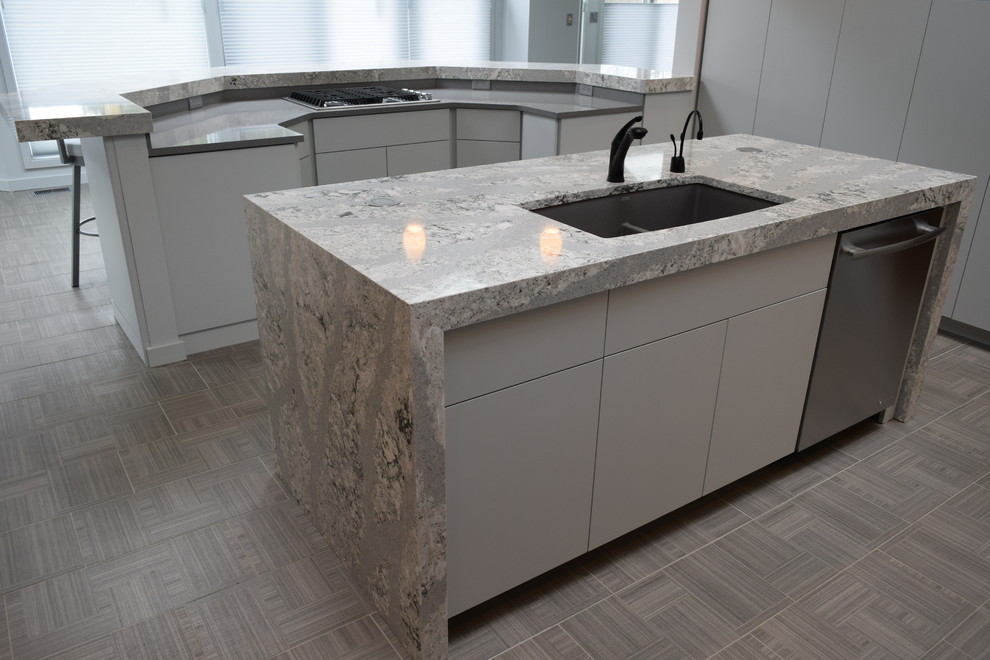 Example of a minimalist ceramic tile and gray floor kitchen design with an undermount sink, flat-panel cabinets, gray cabinets, quartz countertops, multicolored backsplash, glass tile backsplash, paneled appliances, an island and gray countertops