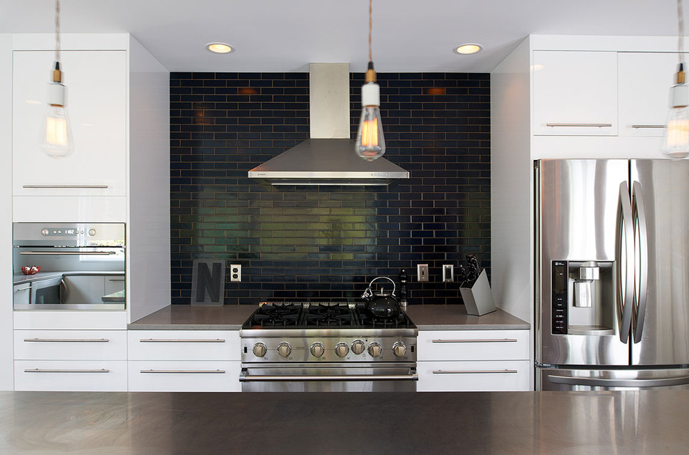 Contemporary kitchen in Minneapolis with flat-panel cabinets, black splashback, subway tile splashback and stainless steel appliances.