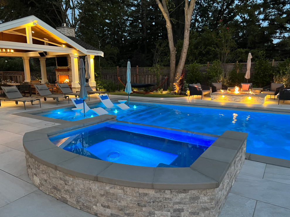 Ejemplo de piscinas y jacuzzis alargados de estilo americano grandes rectangulares en patio trasero con suelo de baldosas