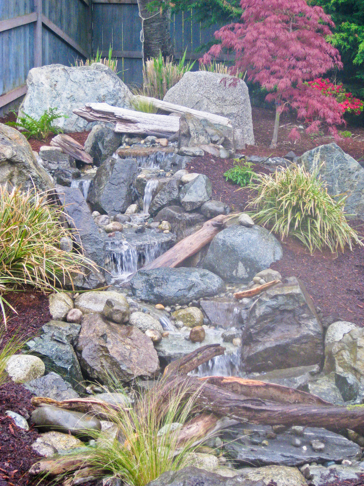 Design ideas for a mid-sized rustic full sun backyard stone water fountain landscape in Seattle for spring.