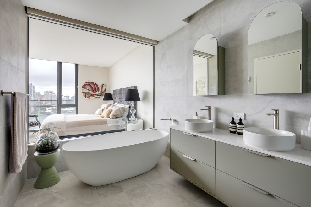 Design ideas for a mid-sized contemporary 3/4 bathroom in Sydney with flat-panel cabinets, grey cabinets, a freestanding tub, a one-piece toilet, gray tile, porcelain tile, grey walls, porcelain floors, a vessel sink, engineered quartz benchtops, grey floor, white benchtops, a double vanity, a floating vanity, a corner shower and a hinged shower door.