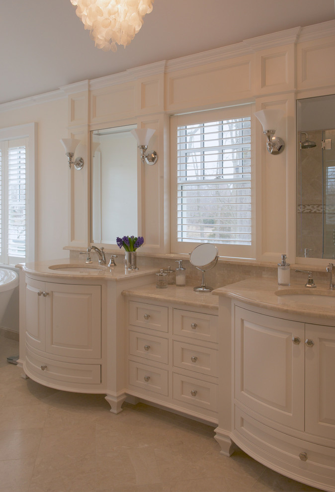 Design ideas for a large transitional master bathroom in New York with raised-panel cabinets, white cabinets, a freestanding tub, an alcove shower, a two-piece toilet, beige tile, stone slab, white walls, porcelain floors, an undermount sink and marble benchtops.