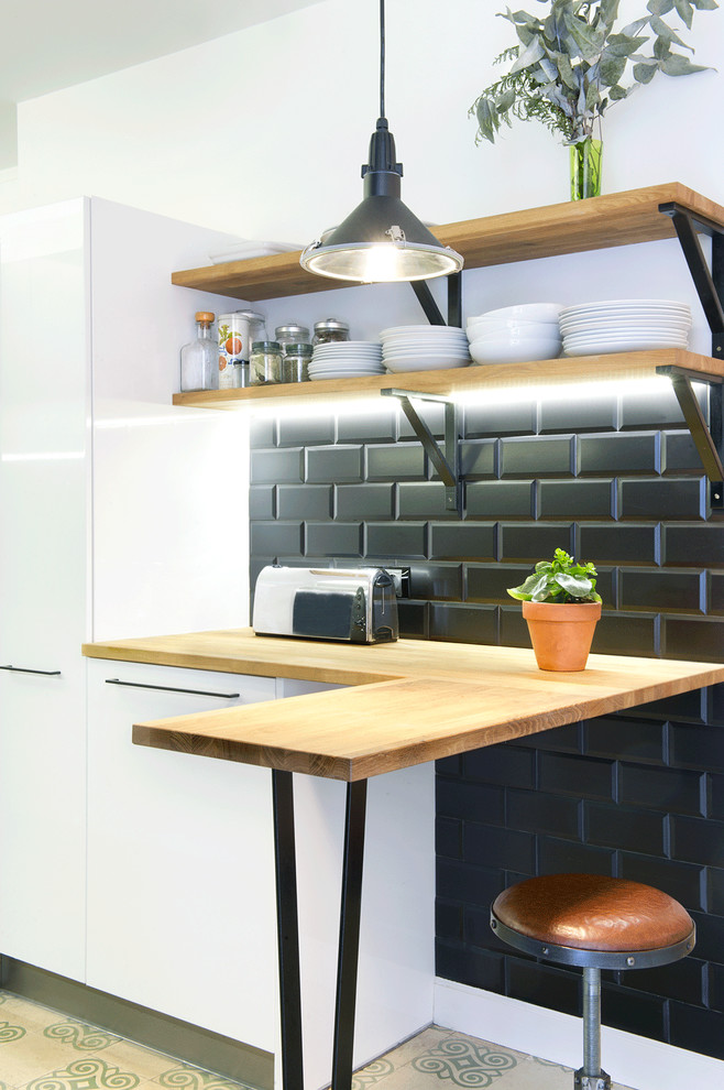 Inspiration for a small scandinavian eat-in kitchen in Madrid with wood benchtops, black splashback, subway tile splashback, a peninsula, flat-panel cabinets, white cabinets and stainless steel appliances.