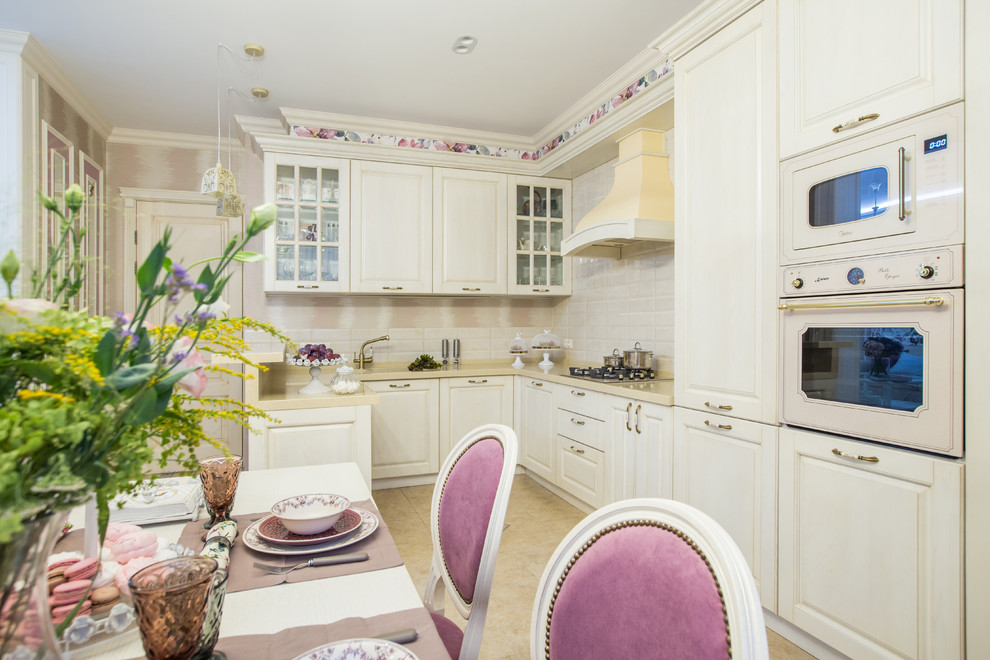 Photo of a transitional l-shaped kitchen in Other with raised-panel cabinets, white cabinets, white splashback, white appliances, no island and beige floor.