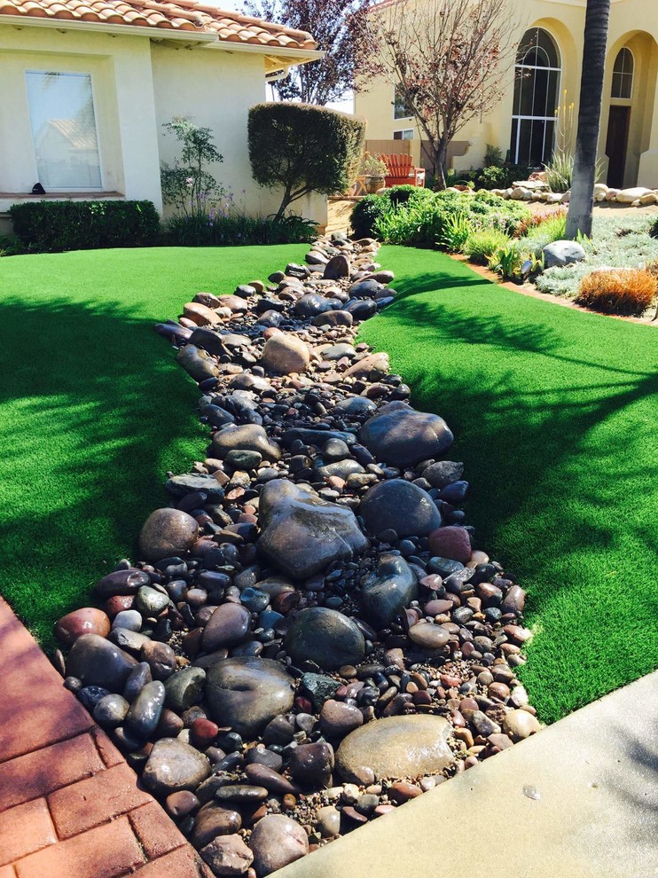 This is an example of a mid-sized traditional front yard partial sun xeriscape in San Diego with river rock.