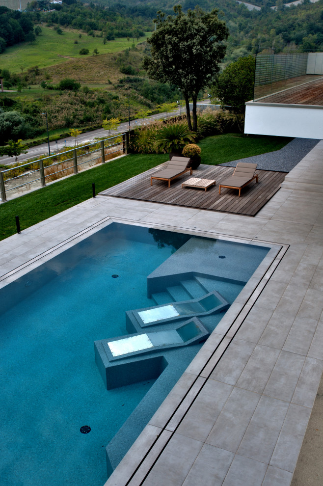 Foto de piscina moderna rectangular con paisajismo de piscina y suelo de baldosas