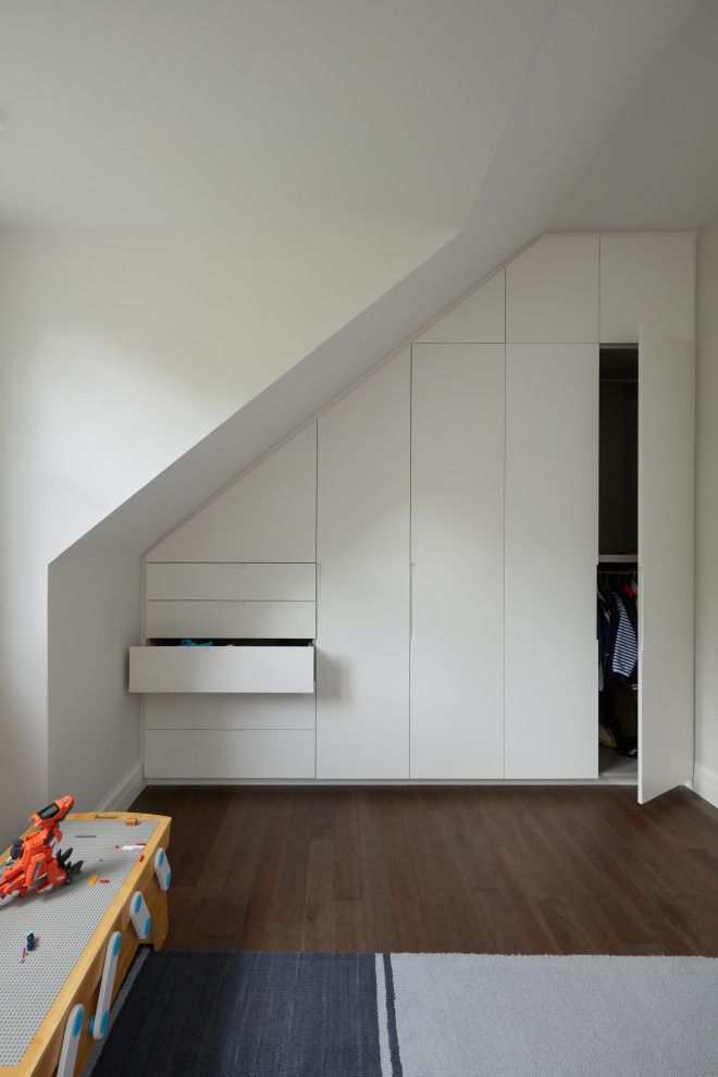 Cette image montre une chambre mansardée ou avec mezzanine minimaliste de taille moyenne avec un mur blanc, parquet foncé, un sol marron et un plafond voûté.