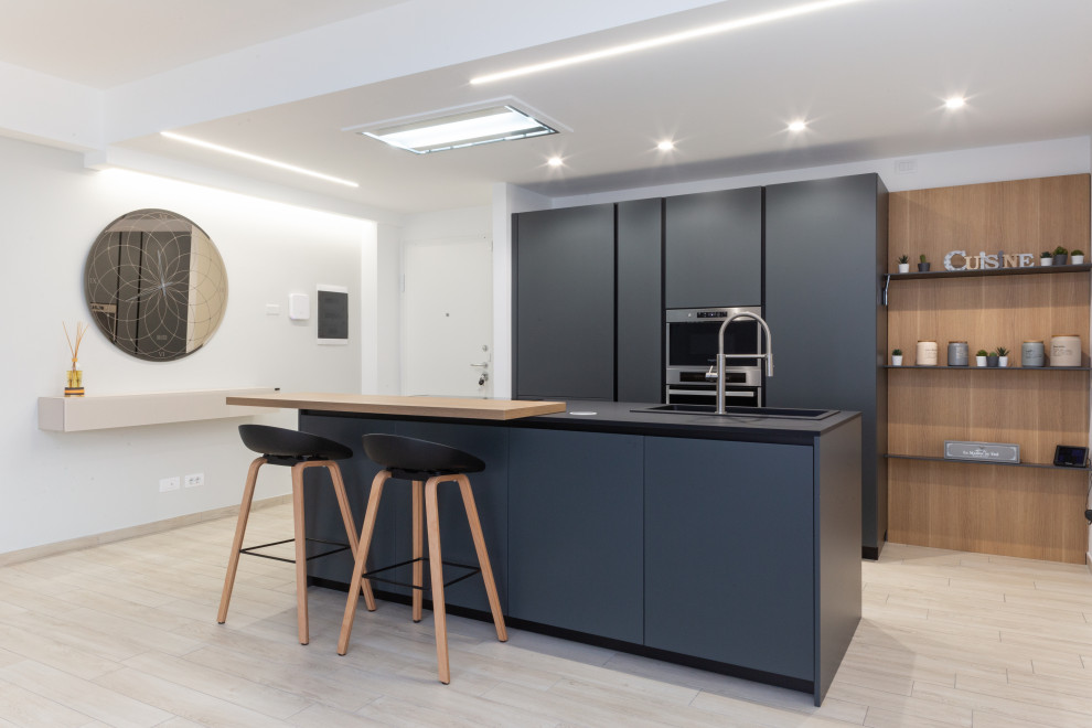Inspiration for a medium sized modern galley open plan kitchen in Rome with a built-in sink, flat-panel cabinets, black cabinets, quartz worktops, black splashback, stainless steel appliances, porcelain flooring, an island, beige floors, black worktops and a drop ceiling.