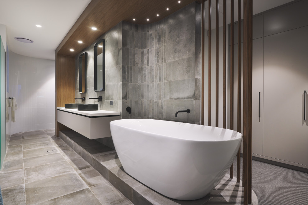 This is an example of a large contemporary master bathroom in Perth with flat-panel cabinets, grey cabinets, a freestanding tub, gray tile, grey walls, a vessel sink, grey floor, white benchtops, a double vanity and a floating vanity.