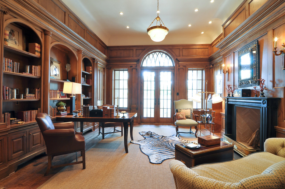Photo of a large traditional study room in Dallas with brown walls, medium hardwood floors, a standard fireplace, a freestanding desk and a wood fireplace surround.