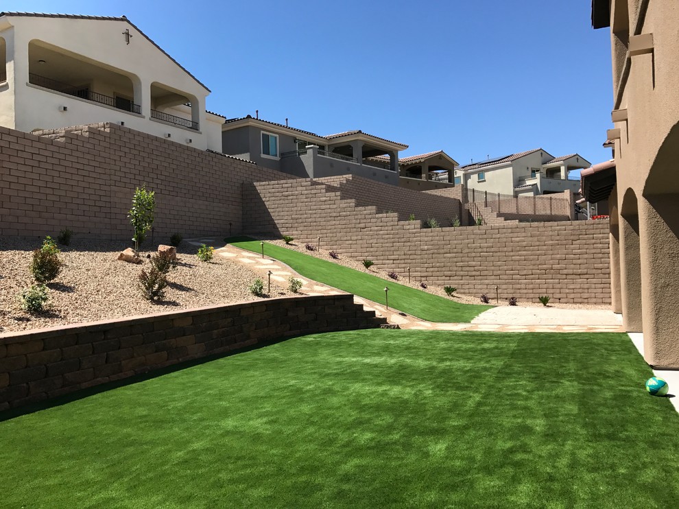 Inspiration for a large contemporary backyard partial sun xeriscape in Las Vegas with a retaining wall and concrete pavers.