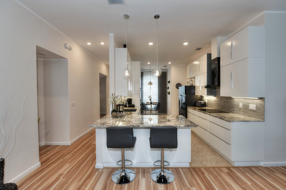 Open concept kitchen - mid-sized contemporary u-shaped porcelain tile open concept kitchen idea in Jacksonville with an undermount sink, flat-panel cabinets, white cabinets, granite countertops, metallic backsplash, metal backsplash and black appliances