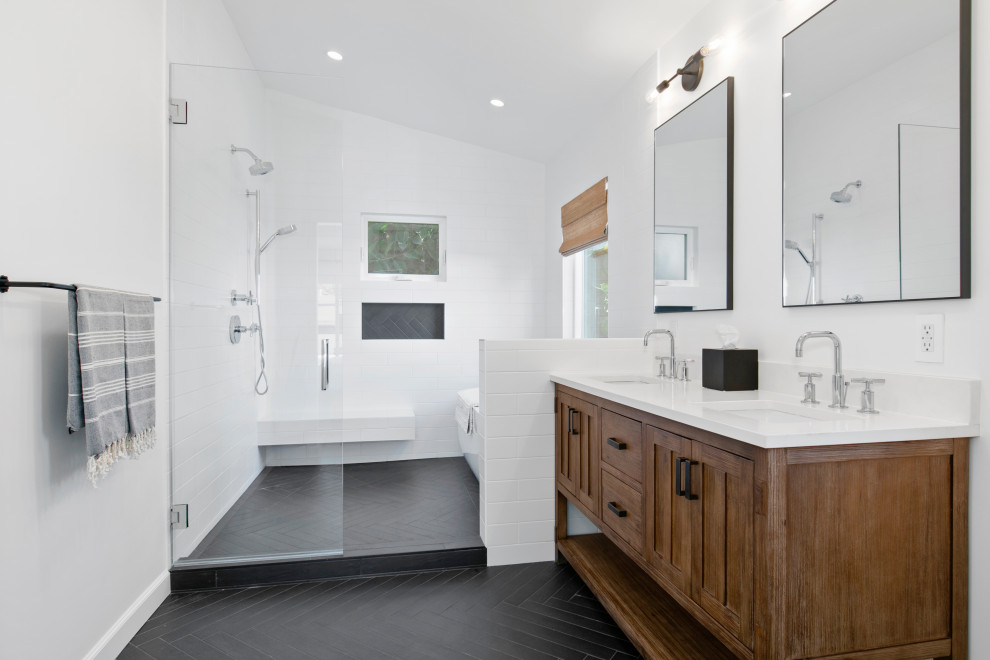 Large transitional master white tile and subway tile porcelain tile and black floor freestanding bathtub photo in Los Angeles with brown cabinets, quartz countertops, a hinged shower door, white countertops, white walls, an undermount sink and shaker cabinets