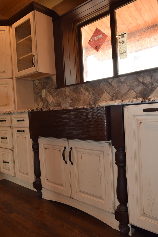 Eat-in kitchen - rustic u-shaped dark wood floor eat-in kitchen idea with a farmhouse sink, raised-panel cabinets, white cabinets, granite countertops, beige backsplash, stone tile backsplash, stainless steel appliances and an island