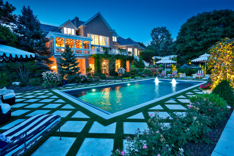 Diseño de piscina alargada tradicional de tamaño medio rectangular en patio trasero con paisajismo de piscina y adoquines de piedra natural