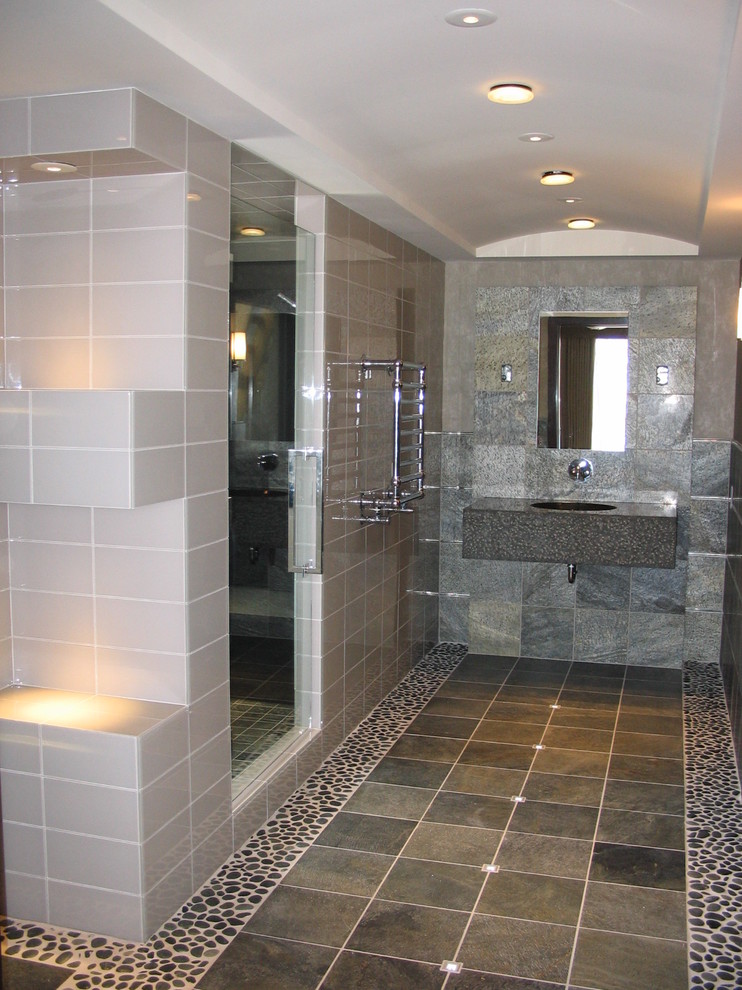 This is an example of a mid-sized contemporary bathroom in Minneapolis with a console sink, flat-panel cabinets, medium wood cabinets, granite benchtops, a two-piece toilet, gray tile, stone tile, grey walls, slate floors and with a sauna.