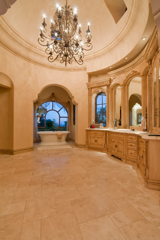 Photo of an expansive mediterranean master bathroom in Phoenix with furniture-like cabinets, brown cabinets, a freestanding tub, an alcove shower, a one-piece toilet, multi-coloured tile, mirror tile, multi-coloured walls, travertine floors, a vessel sink, granite benchtops, multi-coloured floor, an open shower and multi-coloured benchtops.