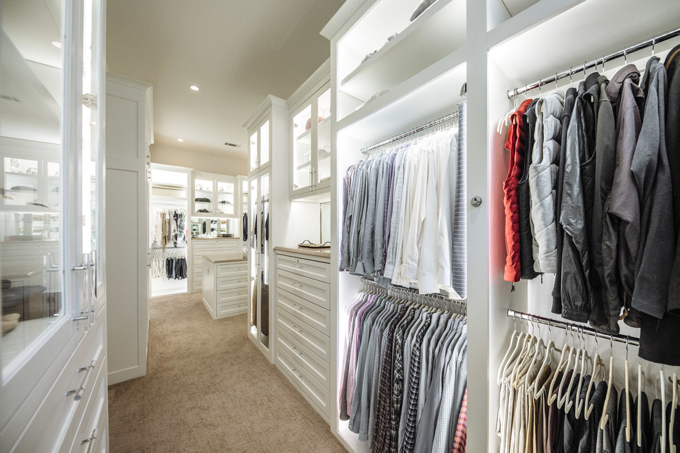 Large transitional gender-neutral walk-in wardrobe in Dallas with beaded inset cabinets, white cabinets, carpet and beige floor.