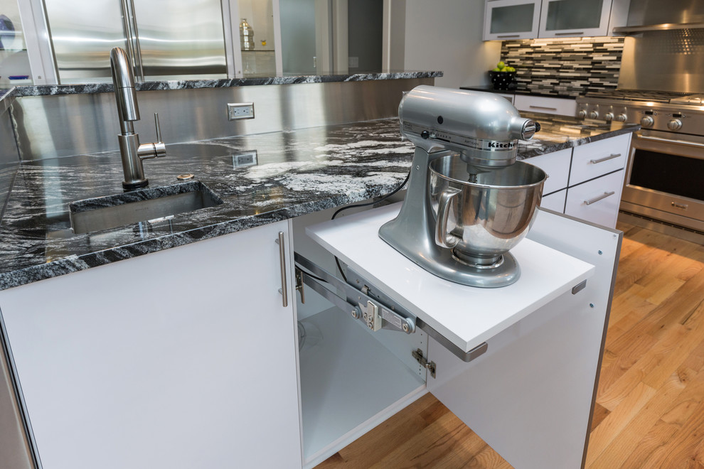 Open concept kitchen - large contemporary u-shaped light wood floor open concept kitchen idea with an undermount sink, flat-panel cabinets, white cabinets, granite countertops, multicolored backsplash, mosaic tile backsplash, stainless steel appliances and an island