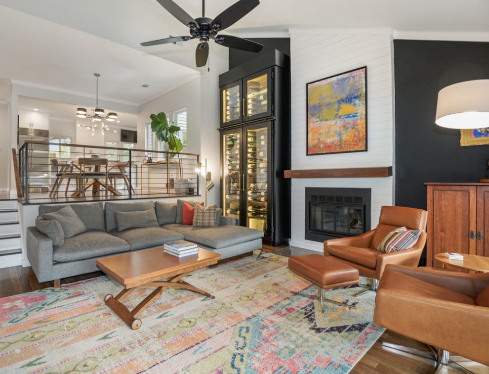 Large contemporary open concept living room in Austin with black walls, medium hardwood floors, a standard fireplace, brown floor and vaulted.