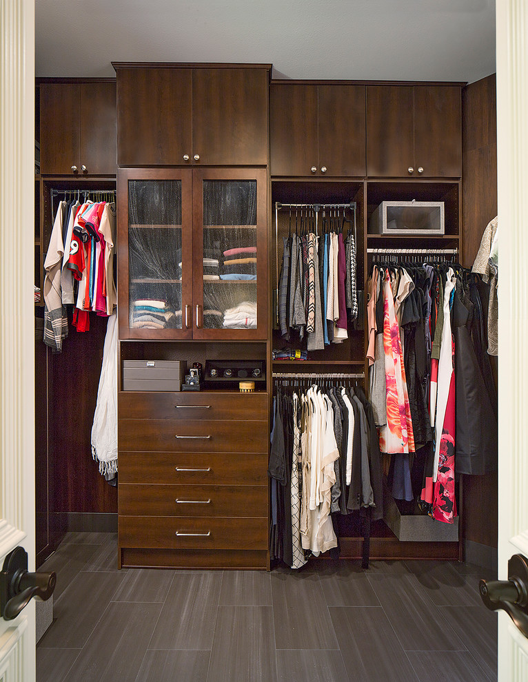 Design ideas for a mid-sized transitional gender-neutral walk-in wardrobe in Dallas with flat-panel cabinets, dark wood cabinets and brown floor.