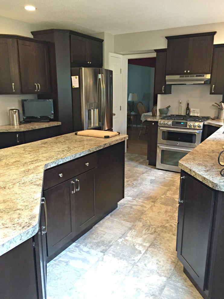 Inspiration for a mid-sized transitional l-shaped limestone floor open concept kitchen remodel with a drop-in sink, shaker cabinets, dark wood cabinets, granite countertops, stainless steel appliances and an island