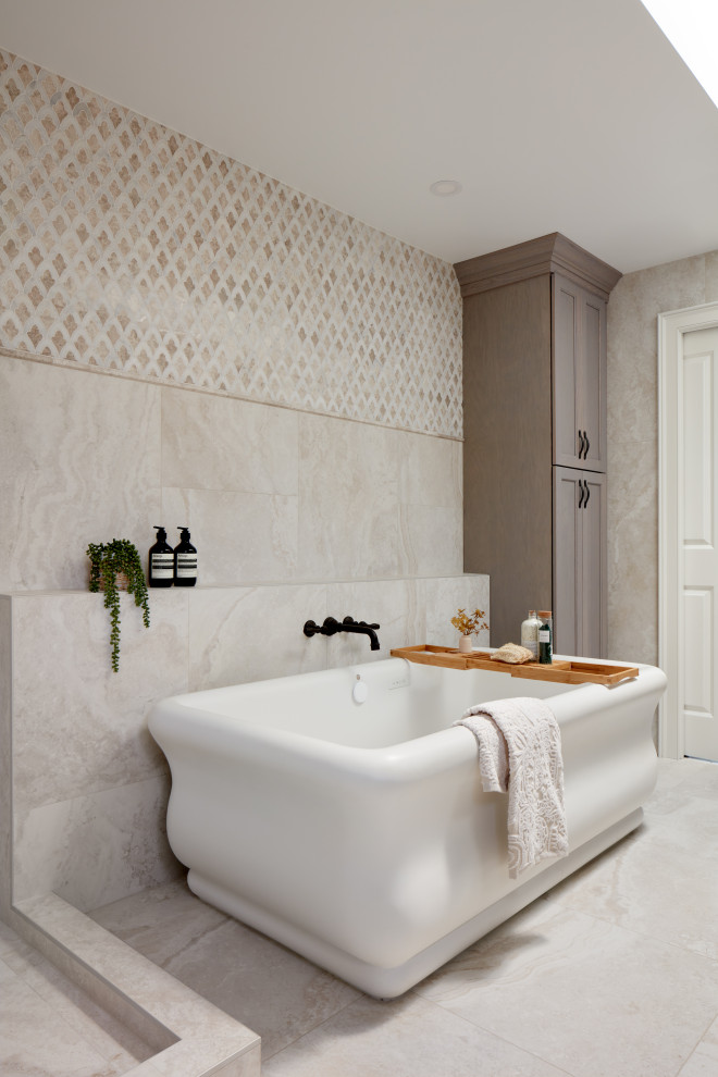Medelhavsstil inredning av ett badrum, med ett fristående badkar, beige kakel och beiget golv