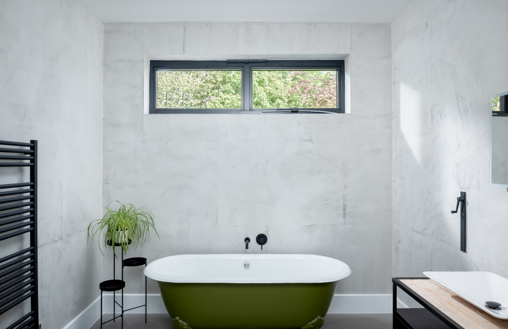 Cette image montre une grande salle de bain principale design avec une baignoire sur pieds et un mur gris.