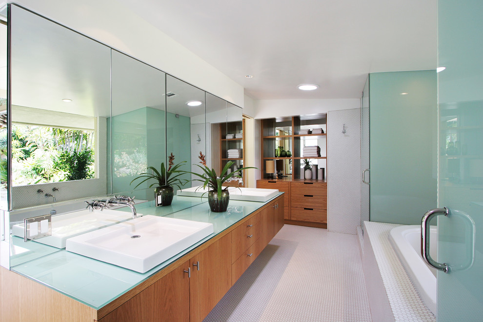 Inspiration for a large contemporary master bathroom in Los Angeles with flat-panel cabinets, medium wood cabinets, a drop-in tub, a corner shower, white tile, mosaic tile, white walls, mosaic tile floors, a vessel sink, glass benchtops, a hinged shower door, white floor and blue benchtops.