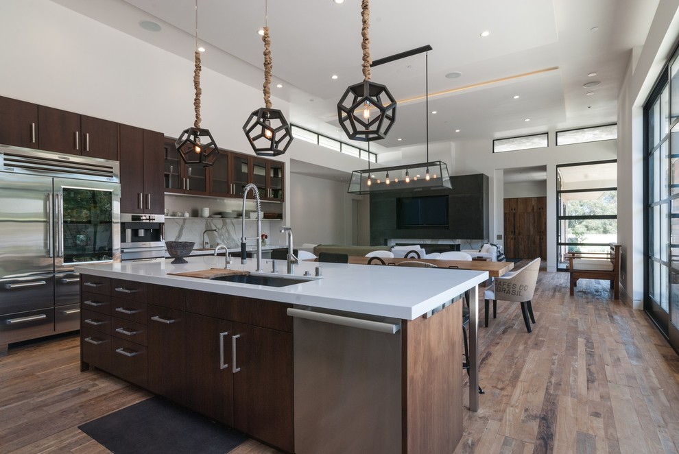 Photo of a large modern l-shaped open plan kitchen in San Diego with an undermount sink, flat-panel cabinets, dark wood cabinets, white splashback, stainless steel appliances, stone slab splashback, quartzite benchtops, light hardwood floors and with island.