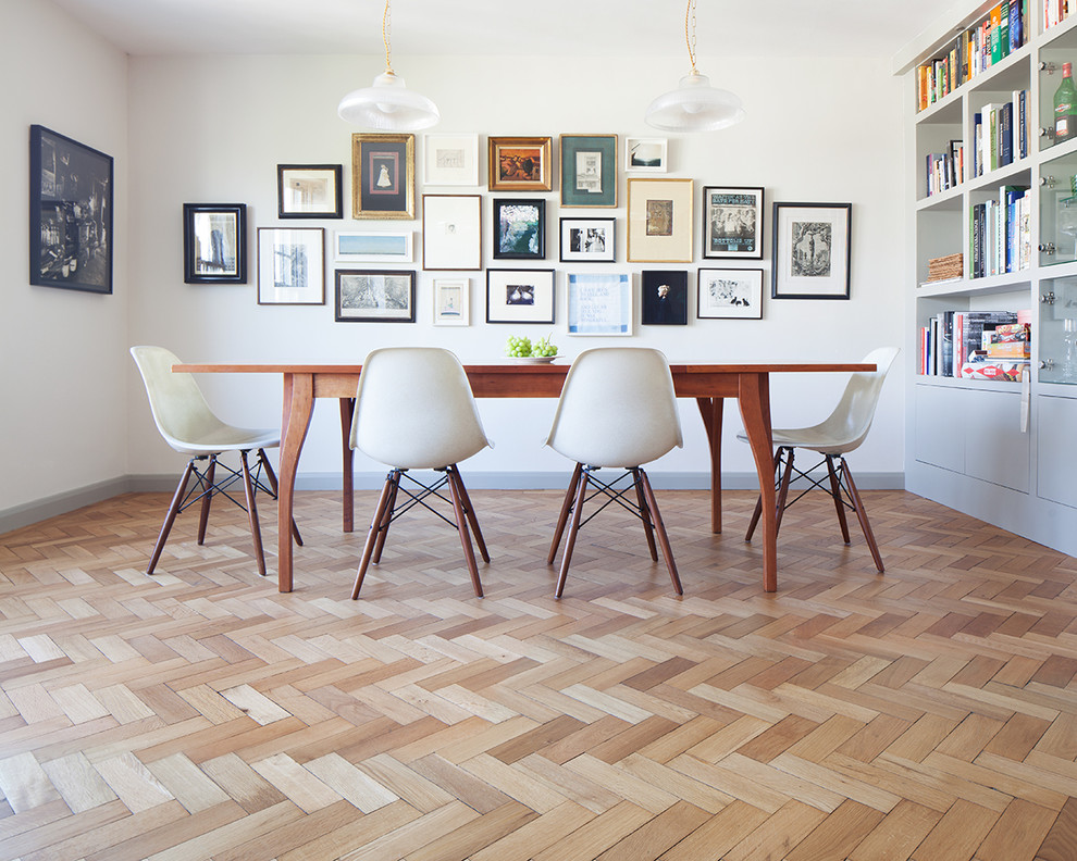 This is an example of a transitional dining room in London with white walls and light hardwood floors.