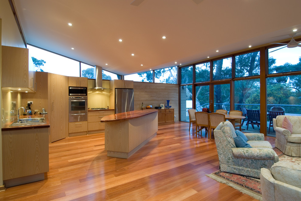 Large contemporary l-shaped open plan kitchen in Adelaide with a double-bowl sink, flat-panel cabinets, light wood cabinets, wood benchtops, glass sheet splashback, stainless steel appliances, medium hardwood floors and with island.