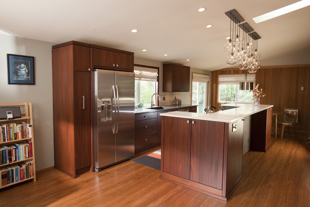 Mid-sized midcentury single-wall eat-in kitchen in Portland with an undermount sink, flat-panel cabinets, dark wood cabinets, quartz benchtops, beige splashback, porcelain splashback, stainless steel appliances, medium hardwood floors, with island, brown floor, multi-coloured benchtop and vaulted.