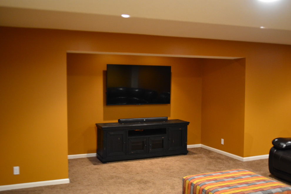 Photo of a large traditional fully buried basement in Kansas City with orange walls, carpet and no fireplace.