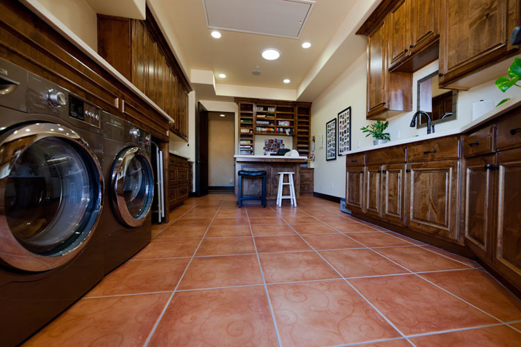 Design ideas for a large mediterranean galley dedicated laundry room in San Luis Obispo with raised-panel cabinets, dark wood cabinets, quartz benchtops, beige walls, ceramic floors and a side-by-side washer and dryer.