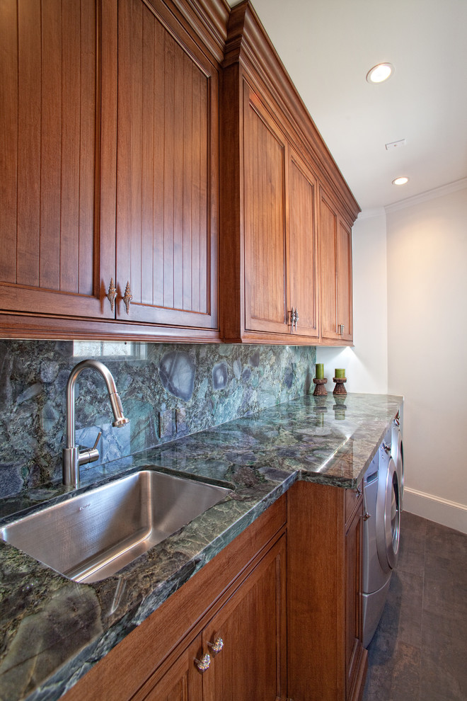 This is an example of a mid-sized traditional single-wall dedicated laundry room in Miami with an undermount sink, medium wood cabinets, granite benchtops, white walls, a side-by-side washer and dryer, green benchtop and recessed-panel cabinets.