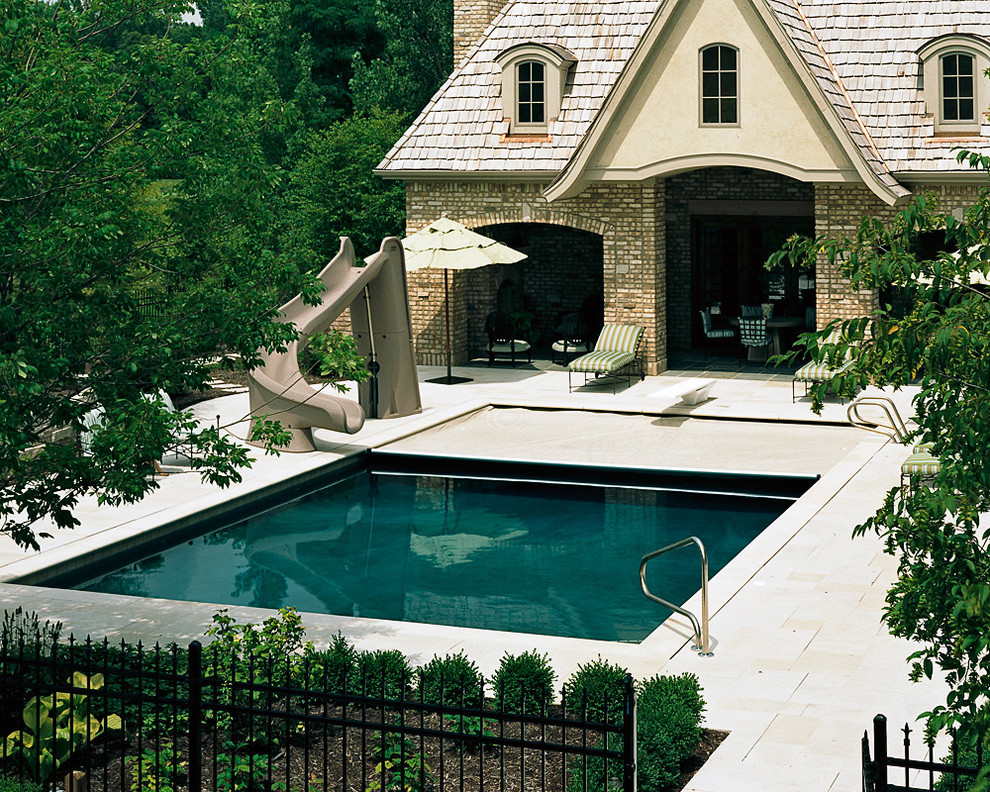 Mid-sized traditional backyard rectangular natural pool in Chicago with a water slide and natural stone pavers.