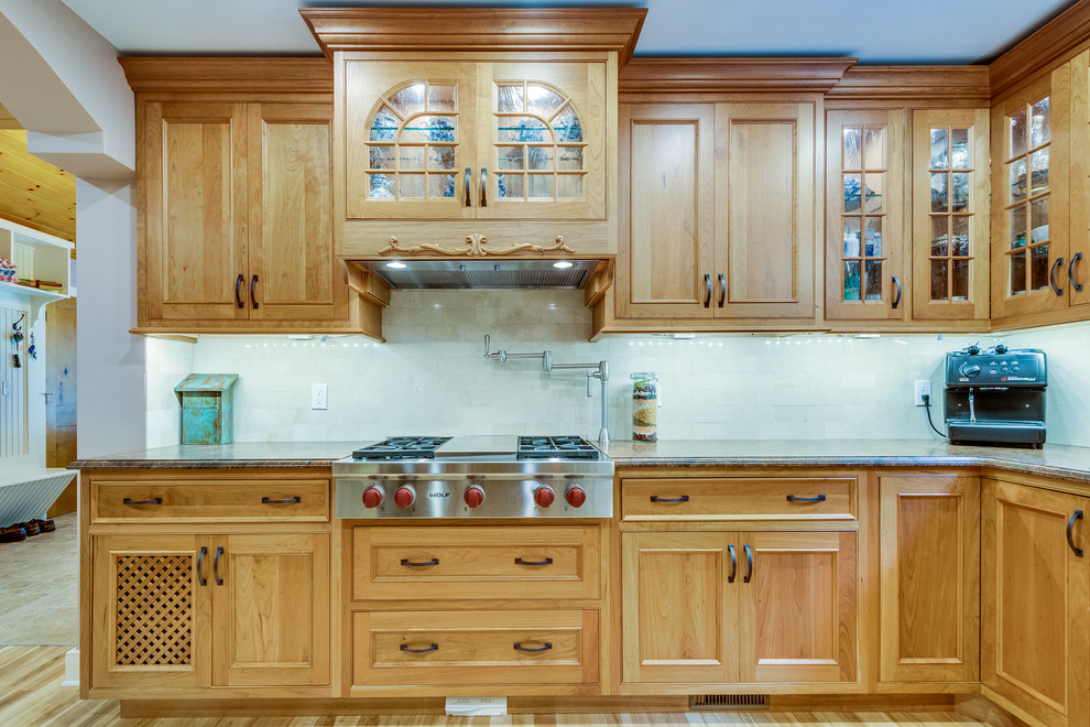 Mid-sized transitional u-shaped medium tone wood floor and brown floor enclosed kitchen photo in Boston with a farmhouse sink, recessed-panel cabinets, medium tone wood cabinets, granite countertops, beige backsplash, stone tile backsplash, stainless steel appliances and no island