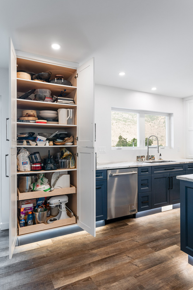 Eat-in kitchen - large transitional u-shaped dark wood floor and brown floor eat-in kitchen idea with an undermount sink, recessed-panel cabinets, blue cabinets, quartz countertops, white backsplash, ceramic backsplash, stainless steel appliances, an island and white countertops